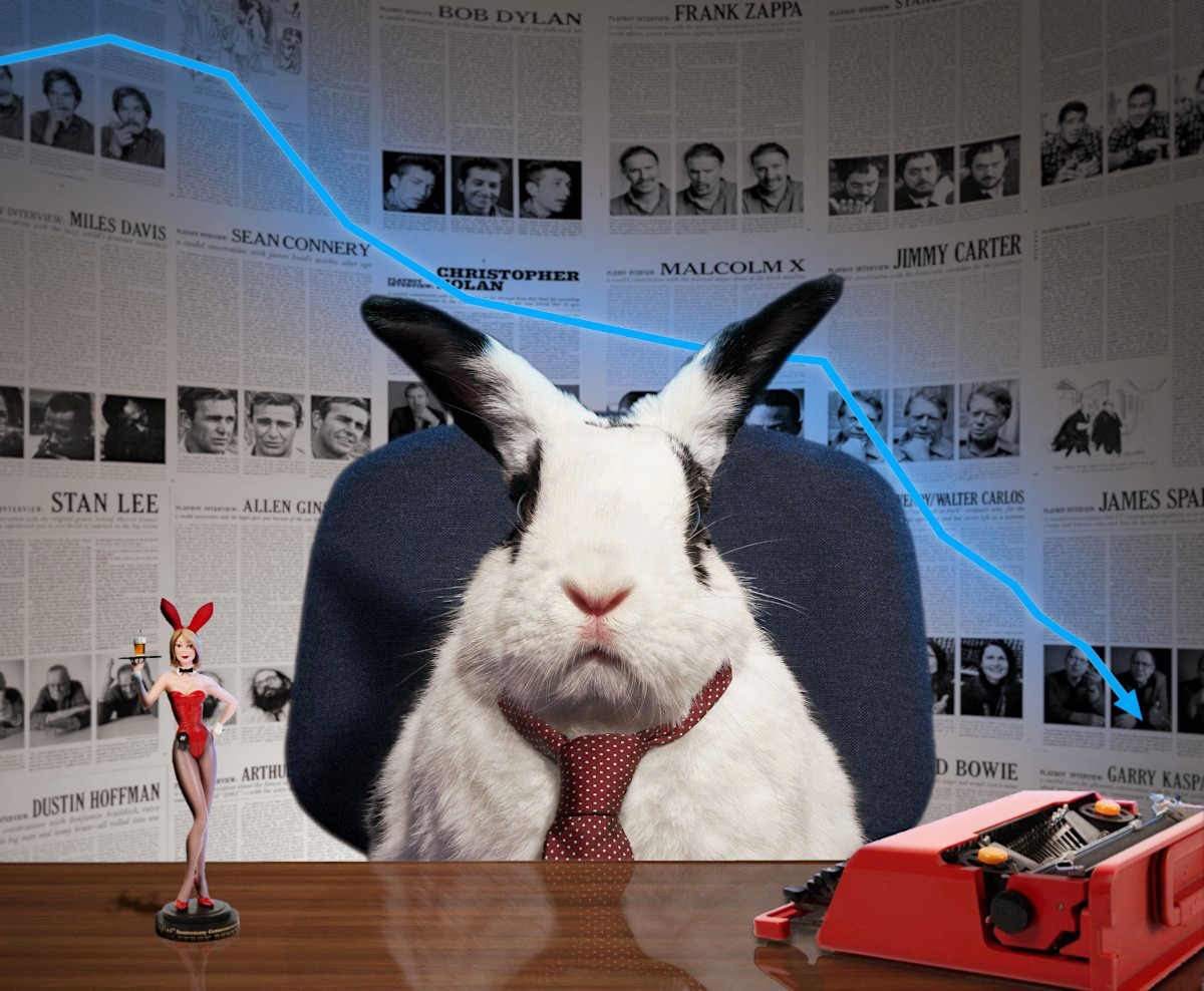 Lapin en cravate assis à son bureau, avec sa machine à écrire et une figurine de bunny girl, devant un mur d'entretiens et une courbe de ventes descendante